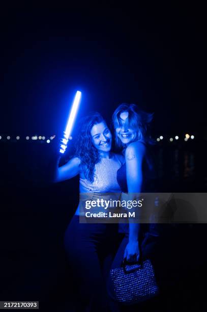 friends dancing holding a laser sword in the beach at night - laser sword stock pictures, royalty-free photos & images