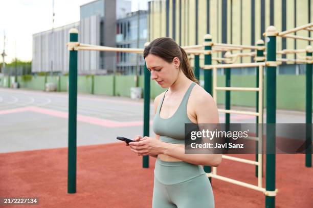 sportswoman using fitness app on smartphone after outdoor workout - calisthenics stock pictures, royalty-free photos & images