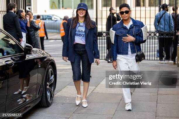 Guest wears navy coat, blazer, capri jeans & a guest wears jeans jacket, white pants outside JW Anderson during London Fashion Week September 2024 on...