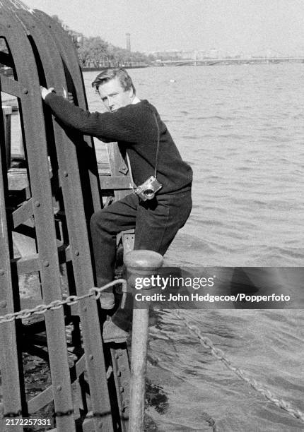 English photographer Antony Armstrong-Jones climbing on to a jetty over the River Thames in London, England circa 1958. Armstrong-Jones would go on...