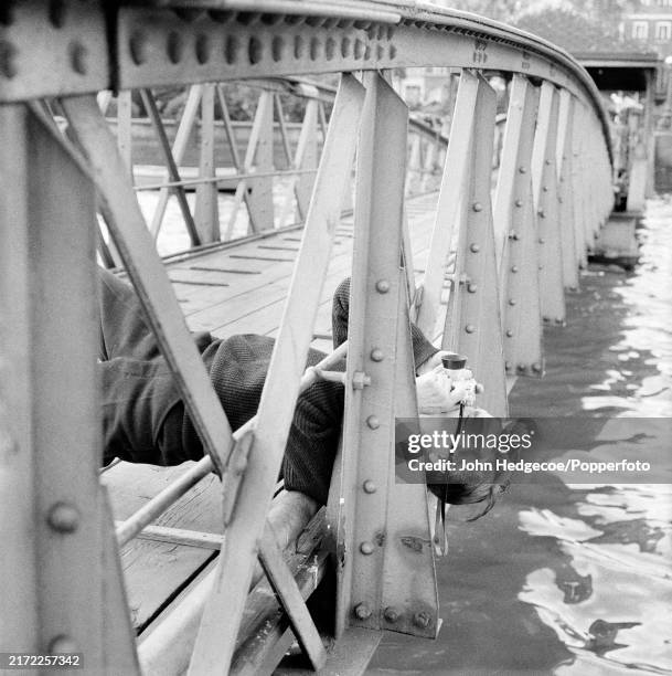 English photographer Antony Armstrong-Jones lying down with his camera on a jetty over the River Thames in London, England circa 1958....