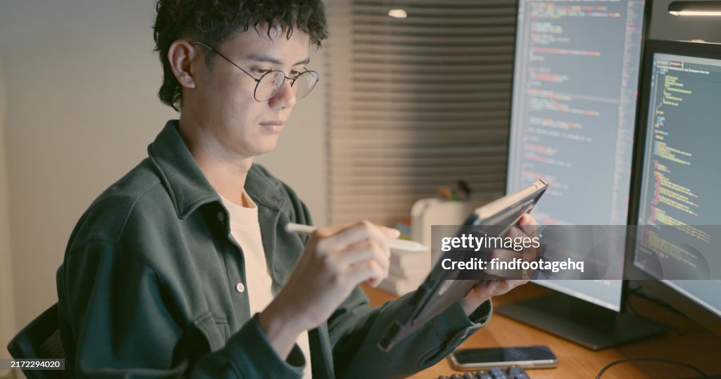 Man Using Digital Tablet for Coding at Desk.