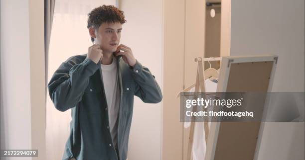 hombre poniéndose la chaqueta frente al espejo. - un solo hombre fotografías e imágenes de stock