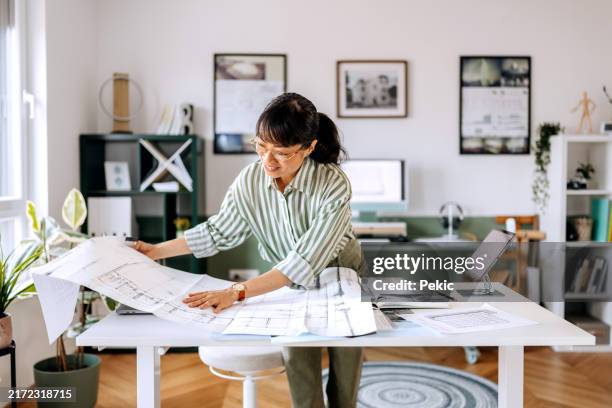 female architect working at her studio, analysing blueprints - arrangement stock pictures, royalty-free photos & images