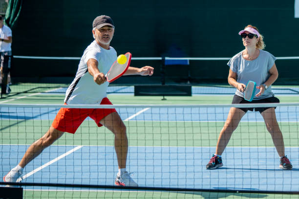 male and female pickleball players are playing male player is shooting forehand ball is on racket female pickleball player is on return horizontal couple pickleball sport still - pickleball stock pictures, royalty-free photos & images