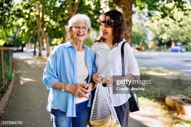 close-up of a senior woman and her granddaughter coming back from grocery shopping - baby boomers at work stock pictures, royalty-free photos & images