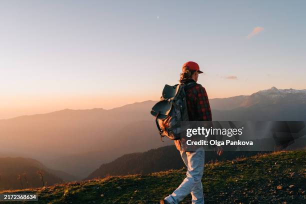 man with a backpack walks in the mountains at sunset - kaukasus geografische lage stock-fotos und bilder