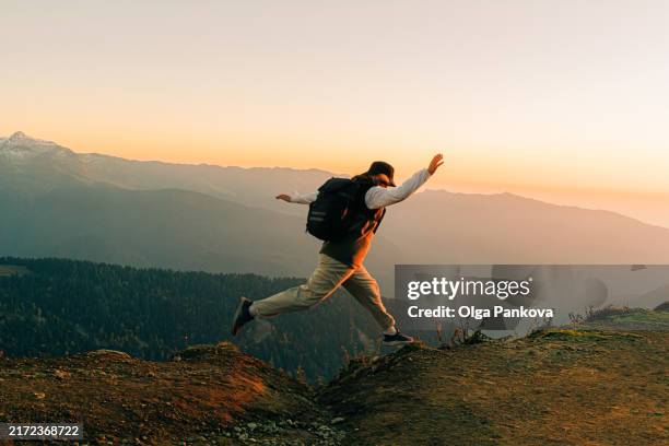 woman jumps with happiness while walking in the mountains at sunset - en la cima del mundo fotografías e imágenes de stock
