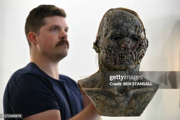 Gallery assistant poses with a silicone mask from Game of Thrones, at a press preview at Heritage Auctions for their sale of props, costumes,...