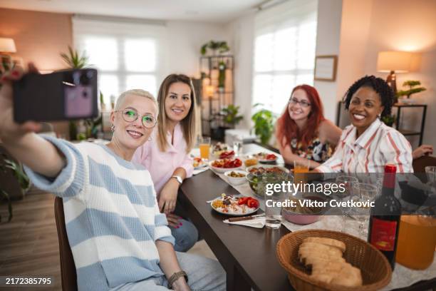 delightful vegan dinner gathering with friends in a cozy, plant-filled dining room celebrating good food and companionship - female friendship stock pictures, royalty-free photos & images