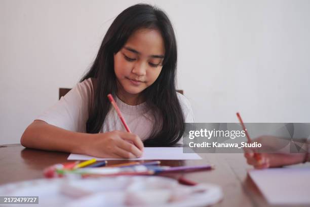 indonesian teenage girl drawing on paper - artist table stock pictures, royalty-free photos & images