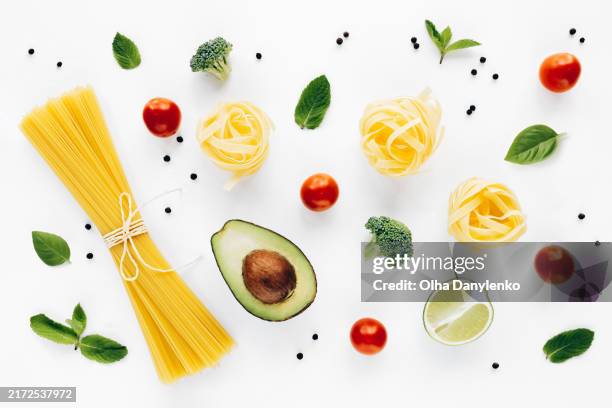 flat lay of fresh ingredients: avocado, pasta, broccoli, cherry tomatoes, and lime on white background. ideal for healthy eating and recipe concepts - spaghetti isolated stockfoto's en -beelden