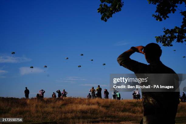 Member of the British armed forces salutes paratroopers from eight NATO member countries jump on to Ginkel Heath in Ede, Netherlands, to commemorate...