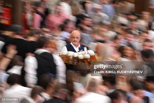 Waiter carries twelve full beer jugs among revellers on the opening day of the Oktoberfest beer festival in Munich, southern Germany, on September...