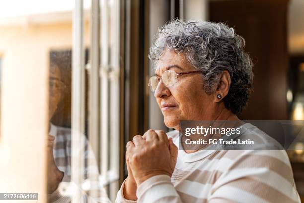 mujer mayor contemplando en casa - mujeres mayores fotografías e imágenes de stock