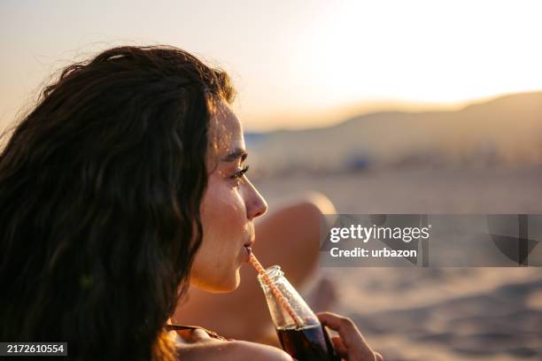 young woman drinking cola on the beach in barcelona in spain - cola stock pictures, royalty-free photos & images