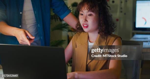 asian male manager accusingly expressing displeasure to young female employee suggesting a tense workplace situation in office at night. esg sustainable business office. - uncomfortable stock pictures, royalty-free photos & images