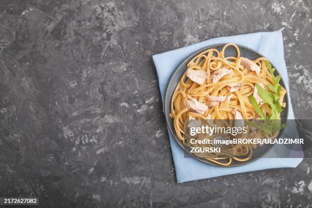 semolina pasta with salmon on a black concrete background and blue textile. top view, flat lay, copy space - flat pasta stock-fotos und bilder