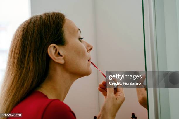 a woman getting dressed in red costume. - lip balm stock pictures, royalty-free photos & images