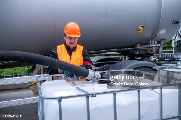 ein techniker füllt öl von einem tanker in einen 1000-liter-ibc-schüttgutcontainer um. - benzintank stock-fotos und bilder