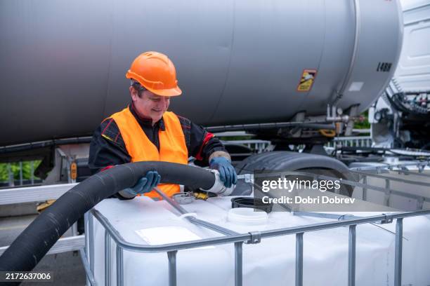 ein techniker füllt öl von einem tanker in einen 1000-liter-ibc-schüttgutcontainer um. - benzintank stock-fotos und bilder