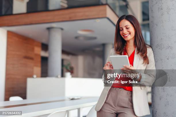 mujer de negocios sonriente en la oficina moderna que sostiene la tableta - chaqueta naranja imágenes fotografías e imágenes de stock