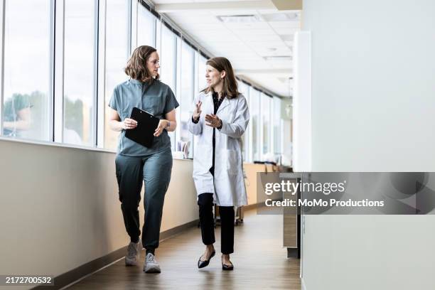 female doctors having discussion in brightly lit hospital corridor - key worker stock pictures, royalty-free photos & images