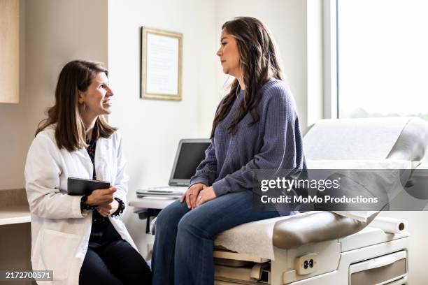 female doctor discussing treatment with female patient in exam room - personnes féminines photos et images de collection