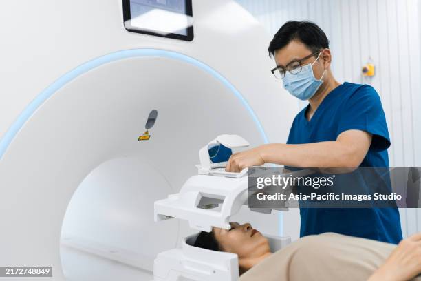 asian male nurse using tomography machine with older woman patient for hospital ct scan at hospital. healthcare concept. - equipamento de exame médico por imagem de diagnóstico imagens e fotografias de stock