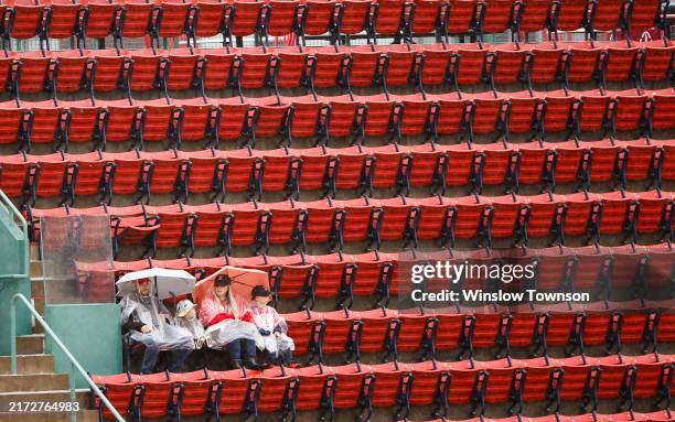 Fans sit in the stands during a rain delay before the game between the Boston Red Sox and the Minnesota Twins was postponed at Fenway Park on...