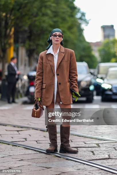 Guest wears dark green head scarf, gold earrings, white buttoned up long sleeve shirt, dark brown oversized blazer jacket, dark brown mini shorts,...