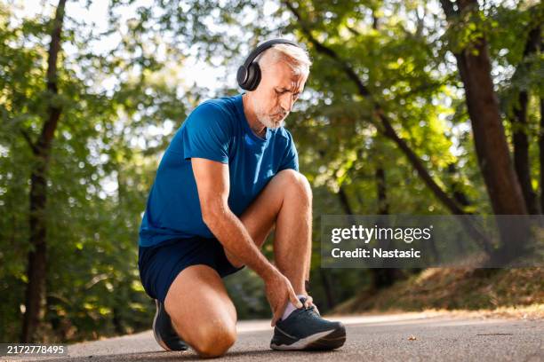 reifer mann, der knöchelschmerzen bei outdoor-übungen hat - knöchel stock-fotos und bilder