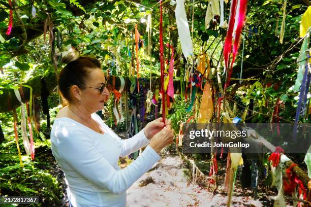 woman making ribbon offerings at a holy well - penzance stock pictures, royalty-free photos & images