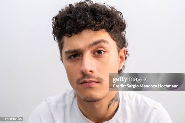 young latino man raising an eyebrow and looking at the camera - raised eyebrows stock pictures, royalty-free photos & images