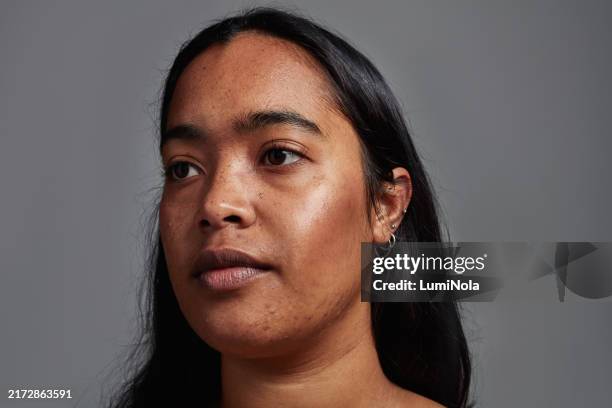 cropped shot of an unretouched image of a beautiful young woman against a grey background - hyperpigmentation stockfoto's en -beelden