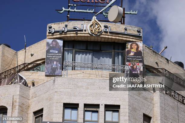 Pictures of slain al-Jazeera journalist Shireen Abu Akleh hang on the facade of the building housing the television station's office in Ramallah in...