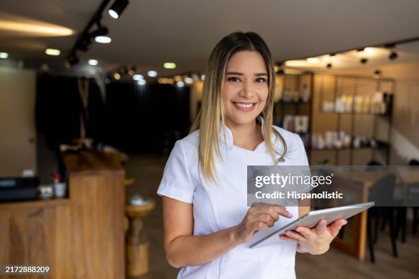 belle coiffeuse travaillant dans un salon de coiffure à l’aide d’une tablette numérique - spécialiste de la beauté photos et images de collection