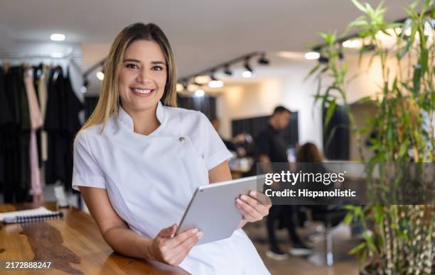 business manager at a hair salon using a digital tablet and smiling - beauty spa stockfoto's en -beelden