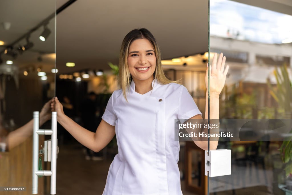 Happy business owner opening the door of her hair salon and smiling