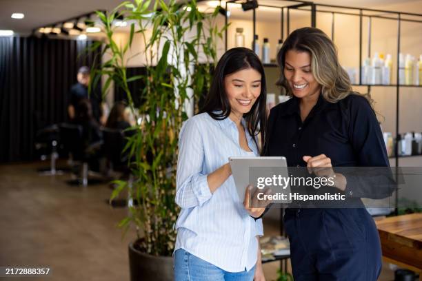 woman at the hair salon looking at options for a haircut recommended by her hairdresser - beauty spa stockfoto's en -beelden