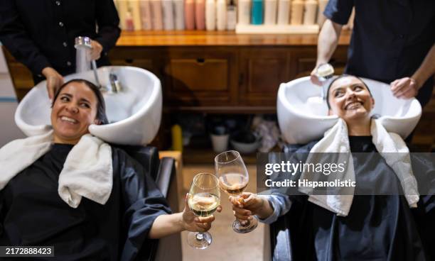 happy women getting pampered at the hair salon and making a toast - hair treatment stock pictures, royalty-free photos & images