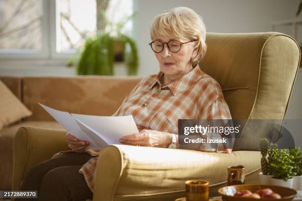 worried senior woman reading documents - medical test results stock pictures, royalty-free photos & images