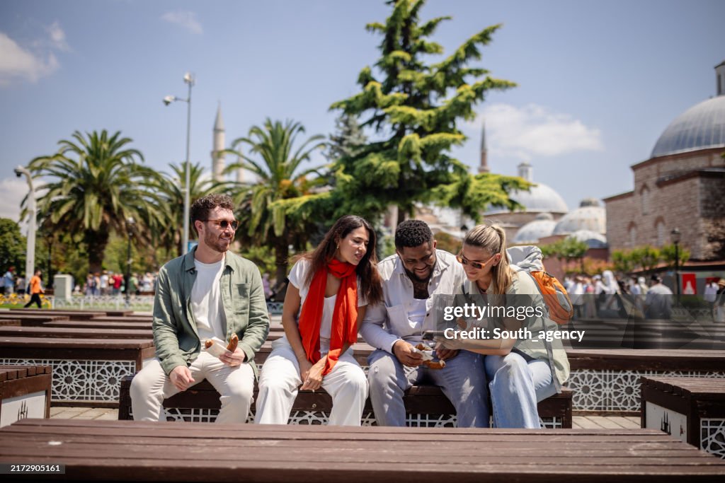 Friends show something on phone in historic city.