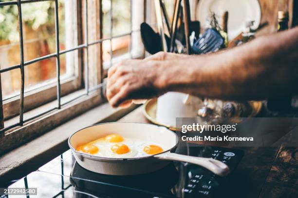 man's hand frying an egg at home. - régime faible en glucides photos et images de collection