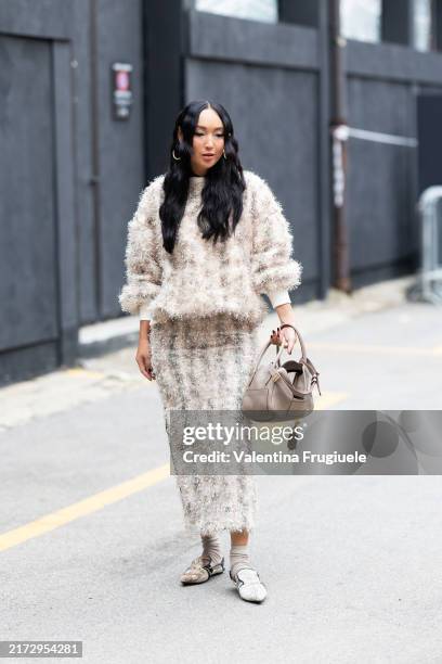 Korlan Madi is seen wearing silver hoop earrings, beige long socks, beige suede mules, a beige leather bag and a beige sparkly coord set made of a...