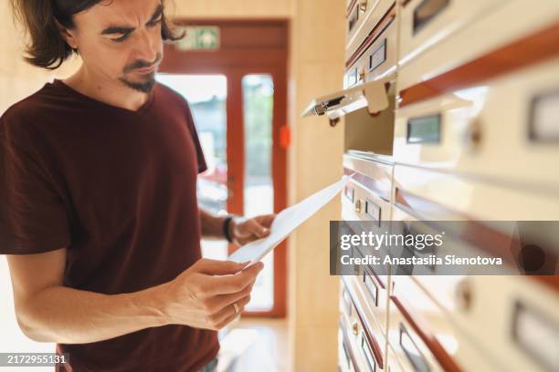 man concerned about contents of letter taken from mailbox - briefkasten stock-fotos und bilder