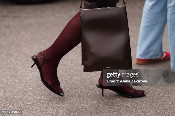 Guest wearing Jil Sander bag is seen outside the Jil Sander show during the Milan Fashion Week Menswear Spring/Summer 2025 on September 18, 2024 in...