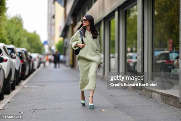 Heart Evangelista wears silver earrings, light green oversized Jil Sander sweater, shiny black leather bag, black sunglasses, a white gold diamond...