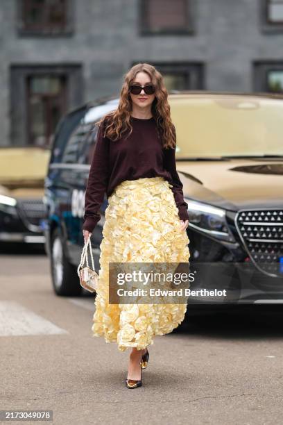 Guest wears black sunglasses, dark red maroon oversized sweater, light yellow floral pattern detail high waisted midi skirt, gold white beaded...