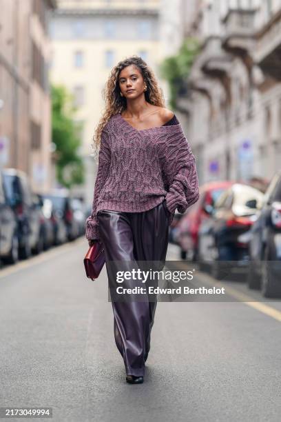 Guest wears dark pink oversized knit sweater, shiny dark brown loose pants, shiny dark red leather bag, outside Boss, during the Milan Fashion Week...